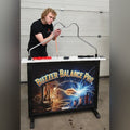 A man playing the MadeForArcade Buzzer Balance Pro buzz wire game at an exhibition stand