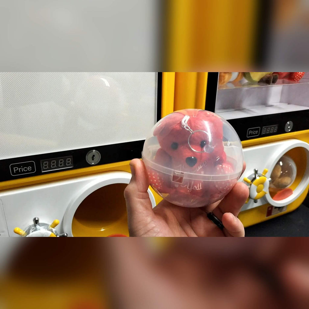 A hand holding a pink capsule from the capsule vending machine