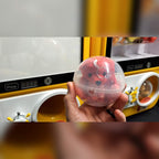 A hand holding a pink capsule from the capsule vending machine