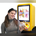 A woman holding a capsule from a yellow MadeForArcade capsule vending machine