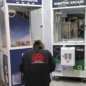 A person playing a white cooled claw machine