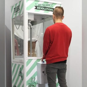 A man playing a striped cooled claw machine
