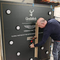 Man installing a custom MadeForArcade batak reflex wall branded for Glenfiddich and the Aston Martin Formula One team