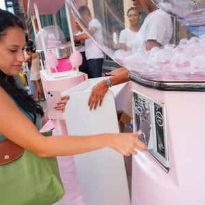 Visitors gathering around the giant white gumball machine at a trade show