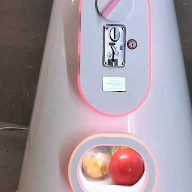 Close-up of the giant gumball machine's coin slot and capsule outlet