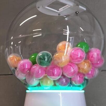 A hand turning the handle on the giant gumball machine