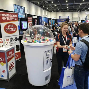 Giant milkshake cup capsule machine at a busy exhibition