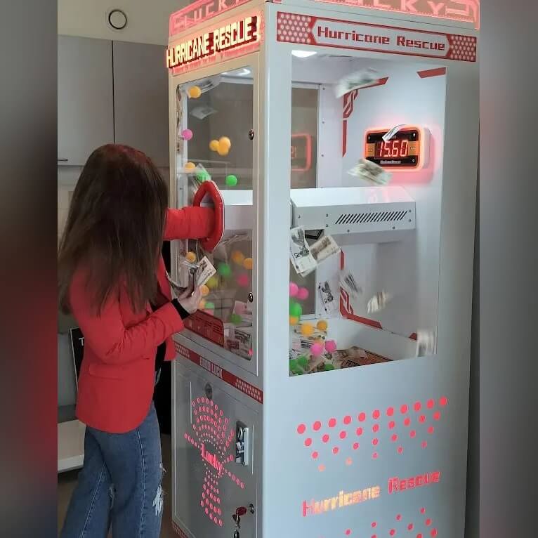 A girl reaching into the money grabber
