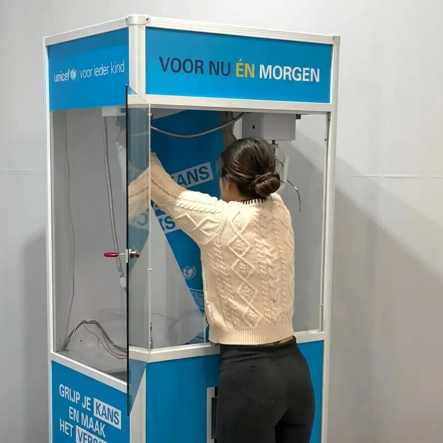A woman playing a blue branded claw machine