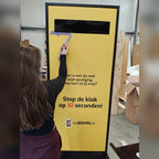 A woman playing a yellow Stop the Clock totem in a showroom