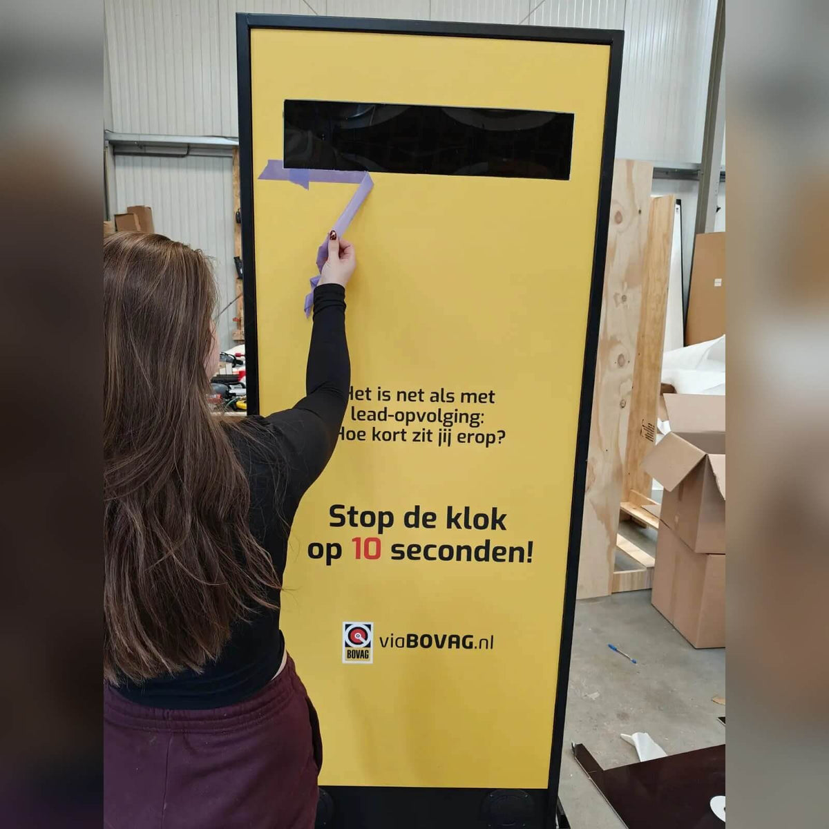 A woman playing a yellow Stop the Clock totem in a showroom