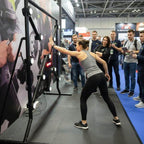 A woman hitting the lit targets on a Strike-a-Light batak machine at a trade show