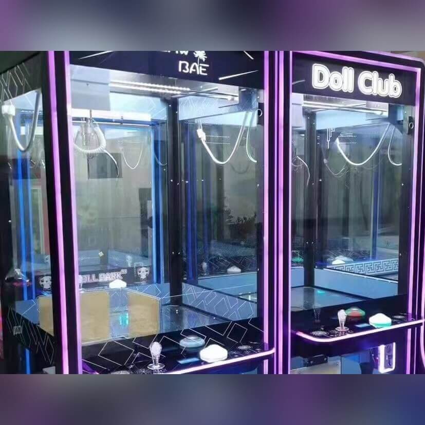Transparent black claw machine glowing purple in a dark room