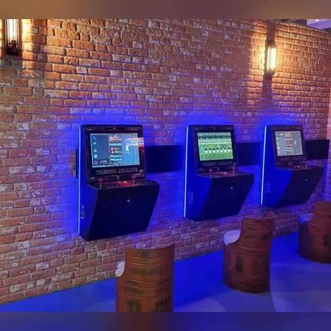 Three wall-mounted arcade machines with backlighting