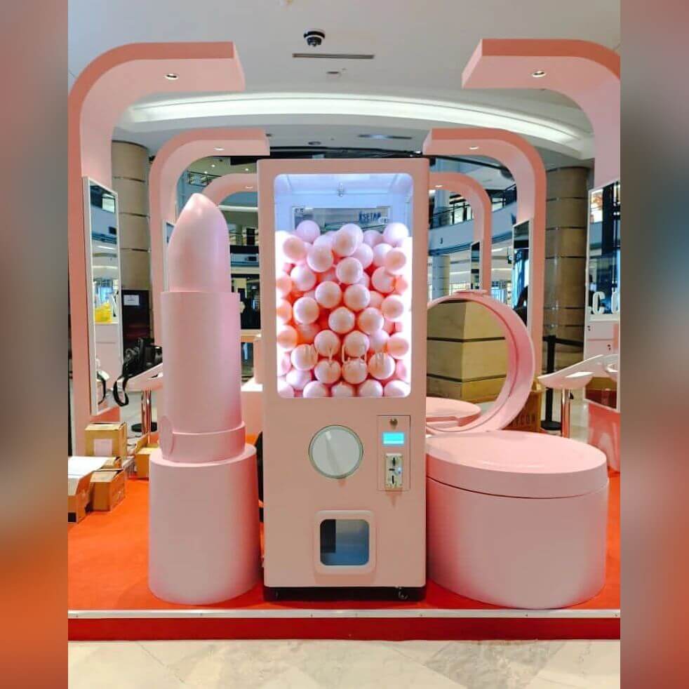 Pink XXL capsule vending tower with a branded wrap in a shop