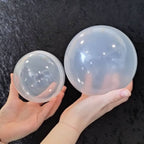 Hands holding two large clear XXL capsules