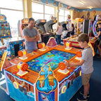 Open Sea Fishing 6 player arcade machine in a UK seaside arcade with a child playing while a parent watches