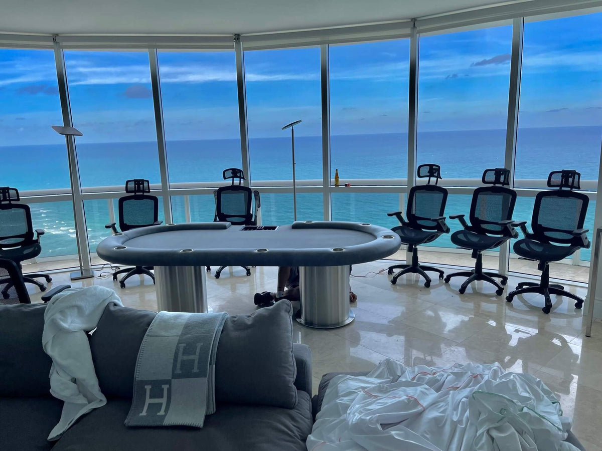 Oval poker table on two pedestals with grey playing surface in a sea view games room