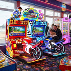 Parkour Motor II DX twin motorbike arcade machine in a UK seaside arcade with a child playing while a parent watches