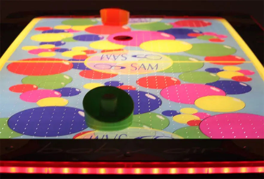 Colourful spotted methacrylate playfield of the SAM Baby Evo with puck and bat