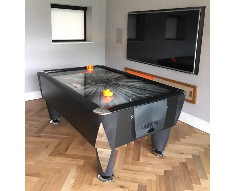 SAM Black Ice II air hockey table in a living room with a wall-mounted TV