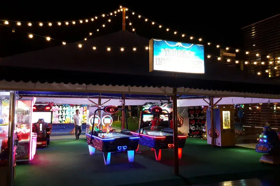 SAM Fast Track Evo II air hockey tables in an outdoor amusement venue at night