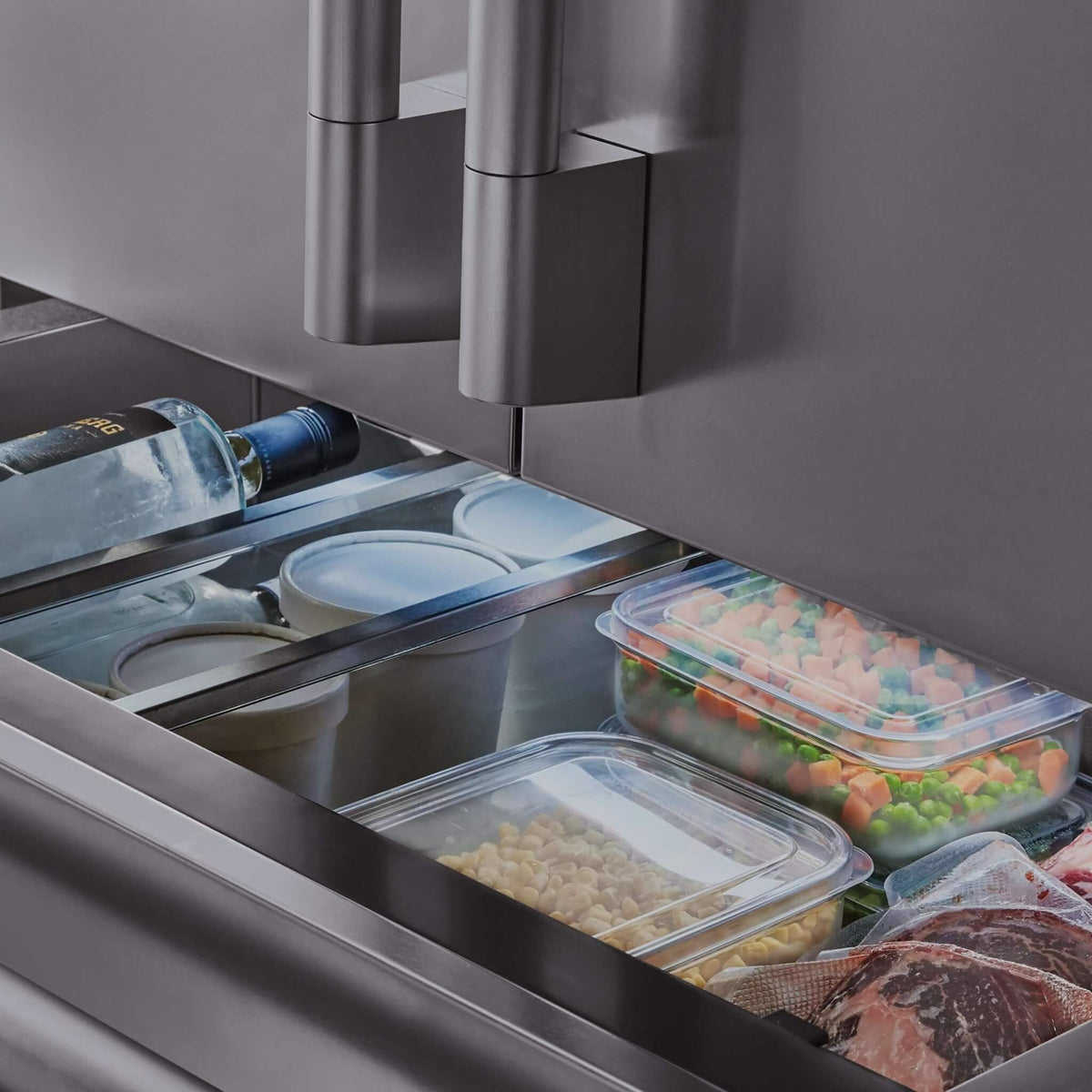 Signature Kitchen Suite convertible drawer pulled open, filled with frozen vegetables, meat and a bottle of water
