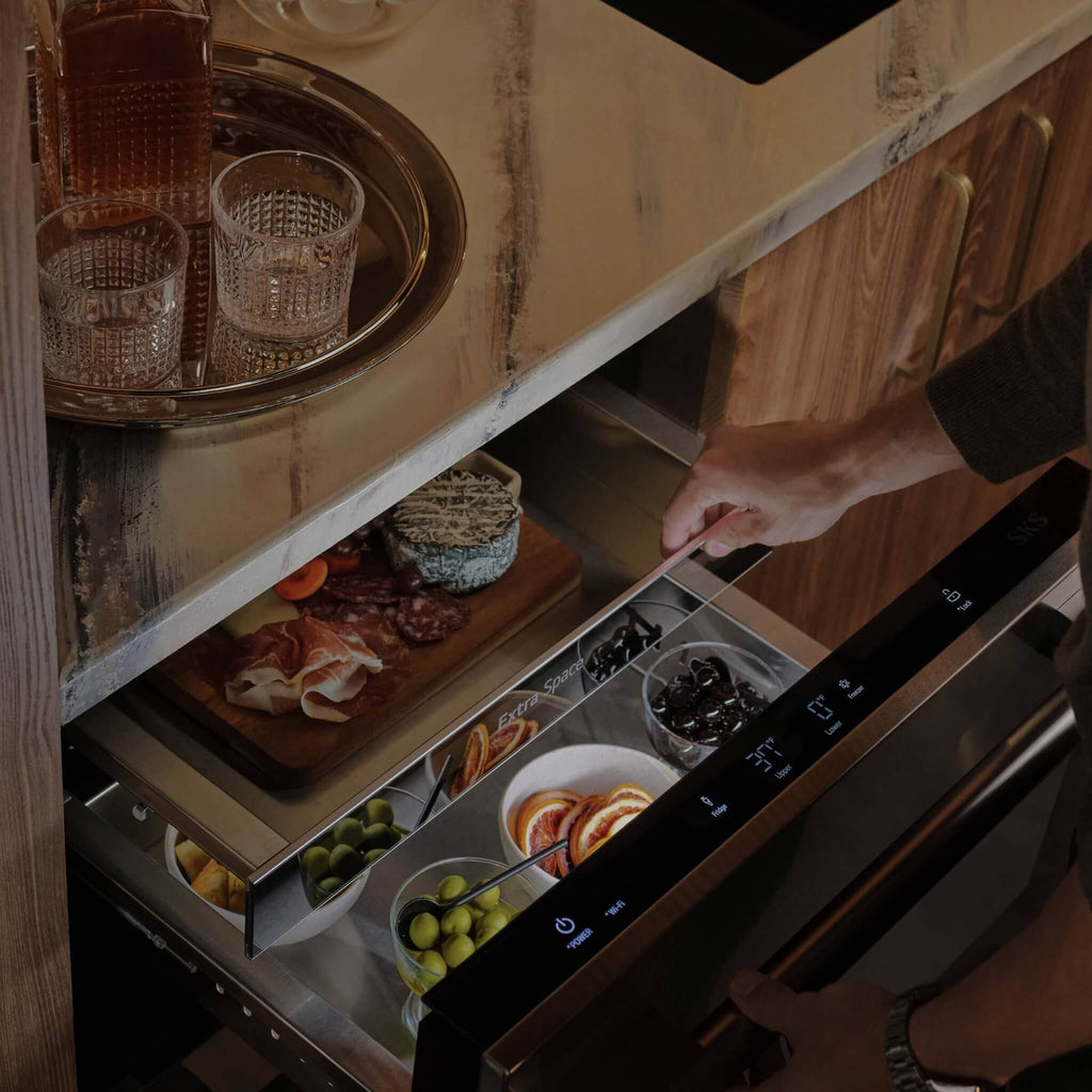 Signature Kitchen Suite fridge drawer pulled open under a marble worktop, filled with party food