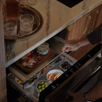Signature Kitchen Suite fridge drawer pulled open under a marble worktop, filled with party food