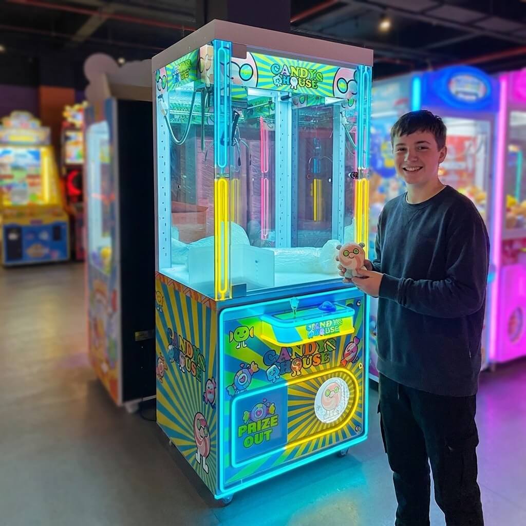 Teenager holding a small plush toy won from the WIK Candy House claw machine in a family entertainment centre