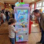 Boy playing the WIK Fun Claw claw machine while his dad watches in a seaside amusement arcade
