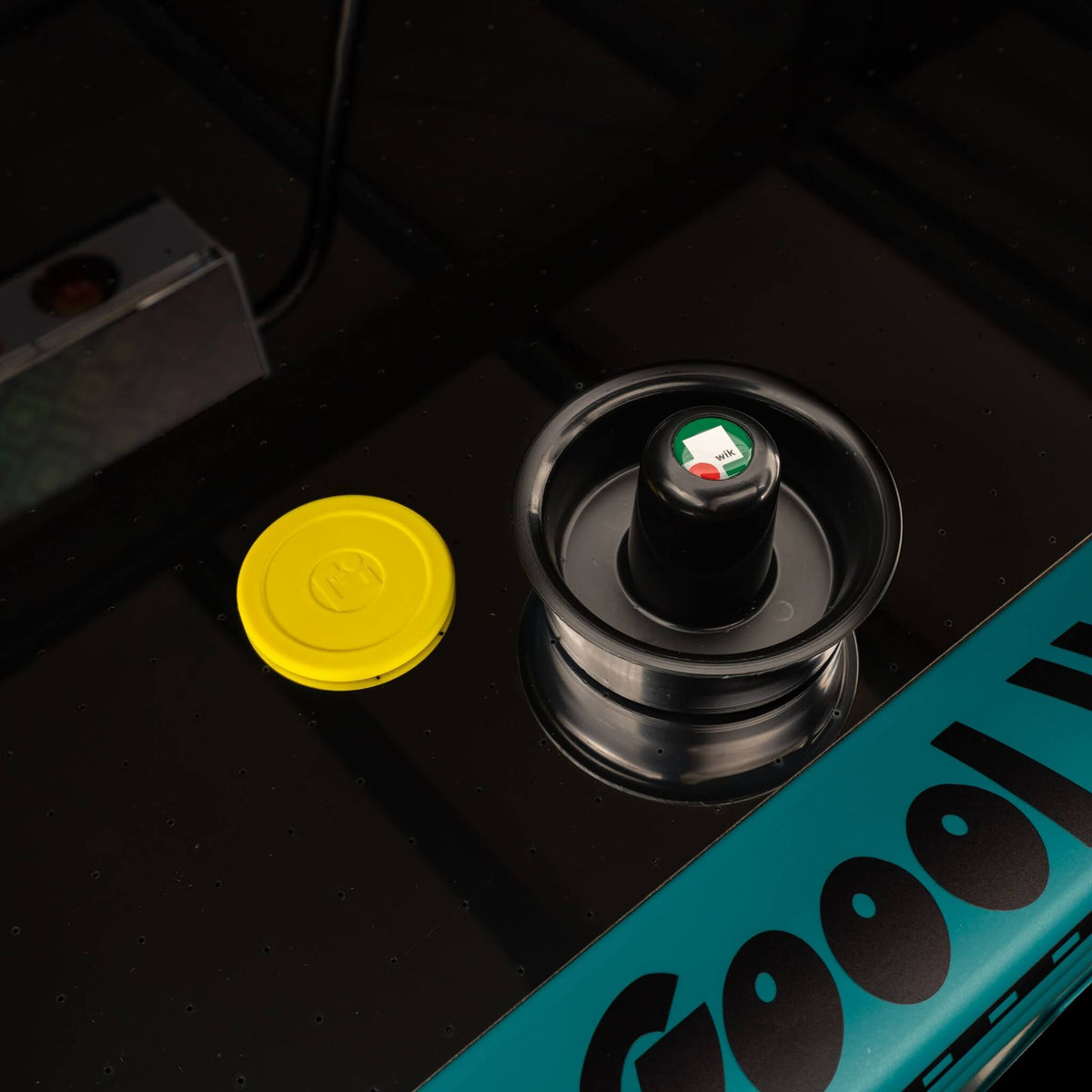Yellow puck and black mallet on the dark playfield of the WIK Golden air hockey table