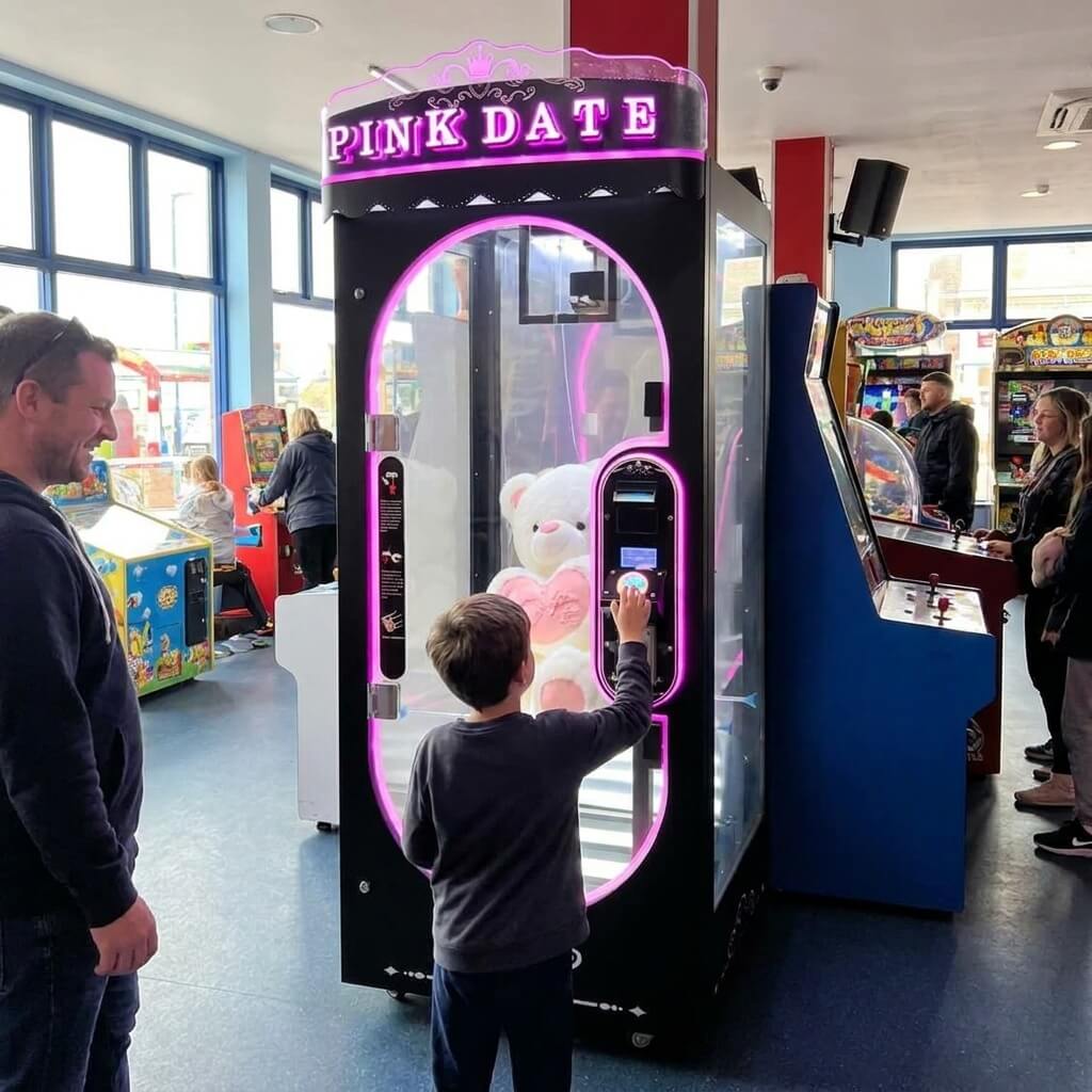 Boy playing the black WIK Pink Date prize machine while his dad watches in an amusement arcade