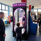 Boy playing the black WIK Pink Date prize machine while his dad watches in an amusement arcade