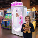 Smiling boy holding a teddy bear won from the white WIK Pink Date in a family entertainment centre
