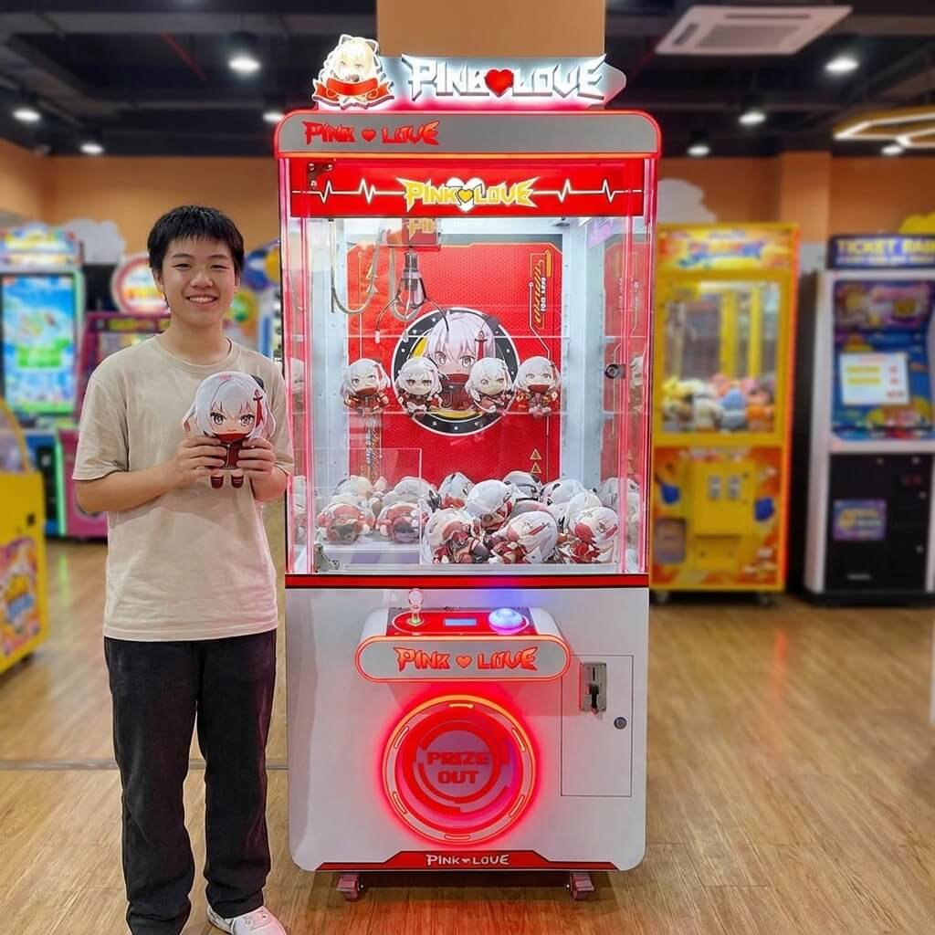 Smiling teenager holding a figure won from the WIK Pink Love claw machine in a family entertainment centre