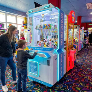 Boy playing the WIK Space Drop prize machine while his mum watches in a seaside amusement arcade
