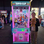 Smiling girl holding a teddy bear won from the WIK Super Clip prize machine in a family entertainment centre
