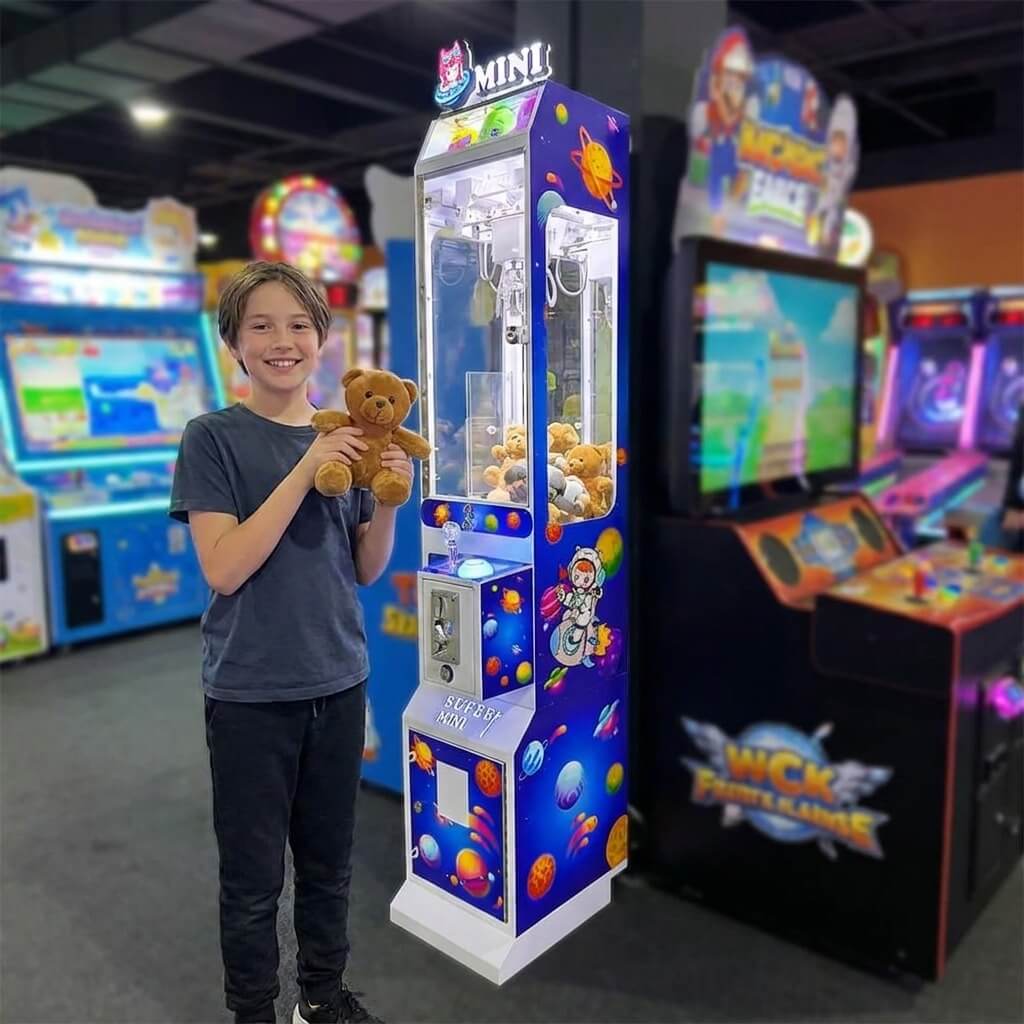 Smiling boy holding a teddy bear won from the WIK Toy Star Mini in a family entertainment centre