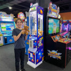 Smiling boy holding a teddy bear won from the WIK Toy Star Mini in a family entertainment centre