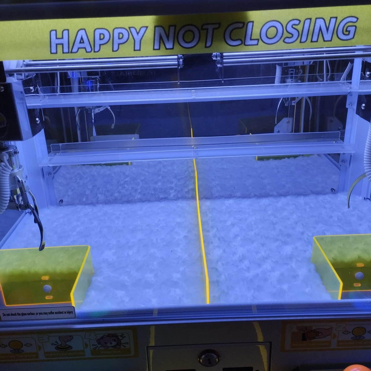 Inside one level of the WIK Trend Star claw machine showing two claws and two prize drop chutes