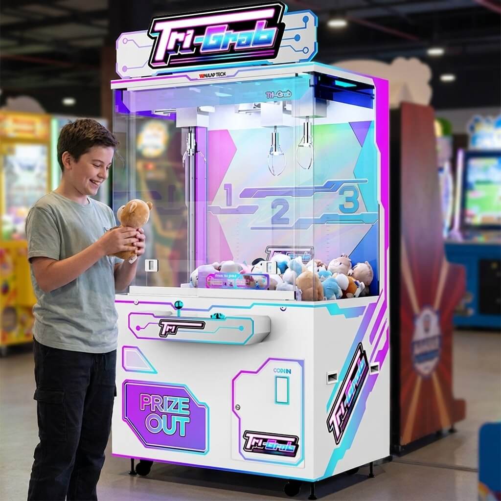 Boy holding a small plush toy won from the WIK Tri-Grab crane machine in a family entertainment centre